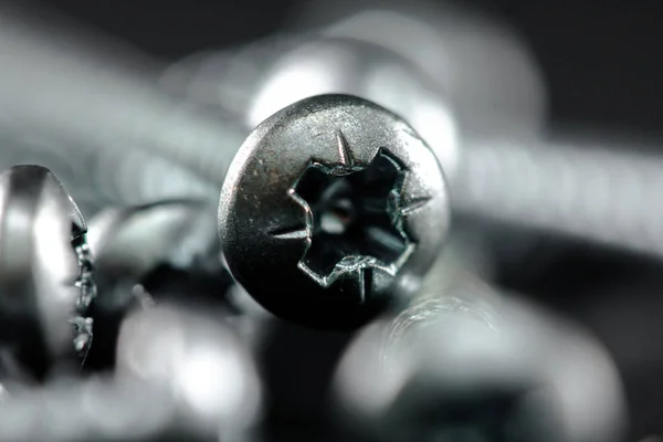 Steel screws grouped on a black background. Tools for DIY. — Stock Photo, Image