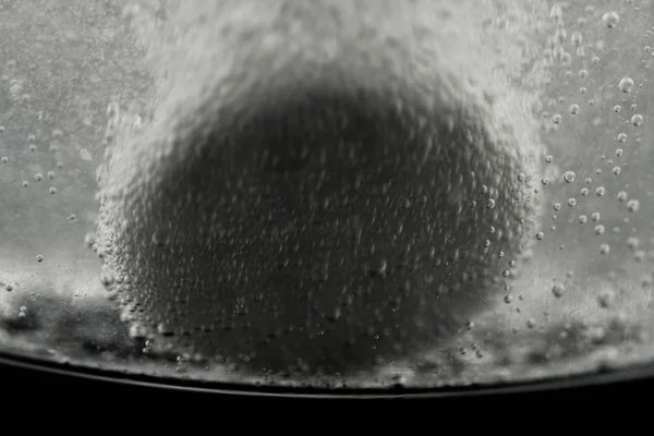 Tableta de medicación blanca que se disuelve en un vaso lleno de agua. Actuar sobre un fondo negro . — Foto de Stock