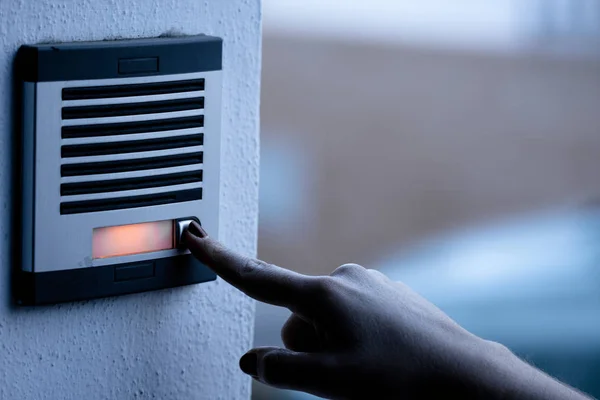 Person calling the bell of a home. Urban technology.