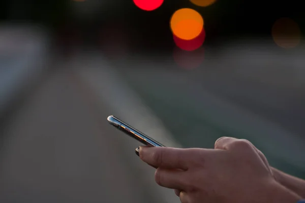 Cep telefonunda, kentsel arka planda, kadın, kentsel teknoloji de yazan kişinin elleri.