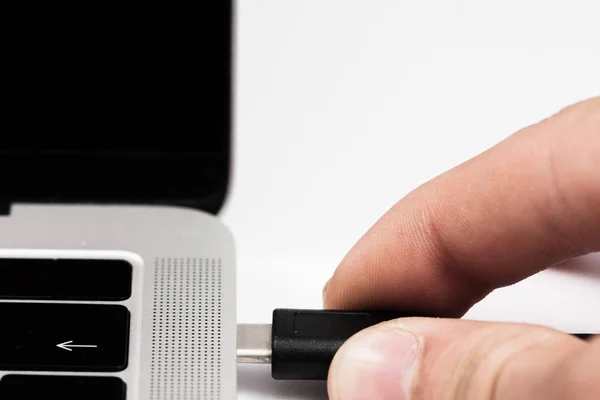 Usb kablosunu dizüstü bilgisayara takılan kişi.