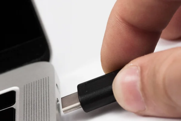 Usb kablosunu dizüstü bilgisayara takılan kişi.