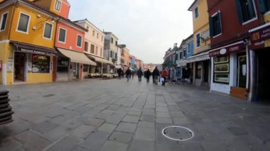 Venedik, İtalya - 14 Aralık 2018: 4k. Ultra Hd. Burano sokaklarında gezen ilk kişi. Öğleden sonra köyün aydınlık ve renkli evleri altında. Tatil.