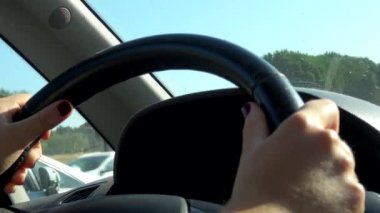4k. Ultra Hd. Arabayı kullanan direksiyondaki kişinin ellerini yakın çekim. Önünde gün ışığı olan bir araç kullanan kadın. İşe giderken. Kadın elleri Teknoloji ve ulaşım