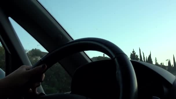 超高清 方向盘上驾驶汽车的人的手的特写镜头 女人驾驶着一辆日光车在前面 在上班的路上女人的手技术和运输 — 图库视频影像