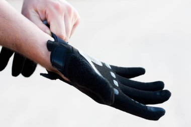 Bisiklete binmeye hazırlanan adam. Beyaz bir adam bisiklete binmek için eldiven takıyor. Harika bir gün batımı ve doğal bir arka plan altında. Spor.
