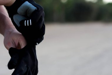 Bisiklete binmeye hazırlanan adam. Beyaz bir adam bisiklete binmek için eldiven takıyor. Harika bir gün batımı ve doğal bir arka plan altında. Spor.