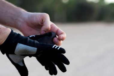 Bisiklete binmeye hazırlanan adam. Beyaz bir adam bisiklete binmek için eldiven takıyor. Harika bir gün batımı ve doğal bir arka plan altında. Spor.