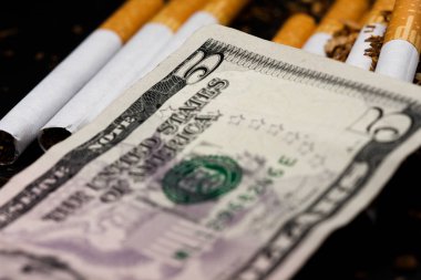 Sigara bazı parçalanmış tütün dağınık, etrafında pennies sikke ve bazı dolar, beyaz arka plan üzerinde izole ile ayrılmış. Tütün hastalıklara neden olabilir.