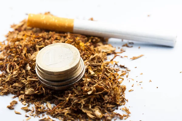 Подрібнений тютюн з монетами євро навколо, ізольований на білому тлі. Тютюн може спричинити захворювання в організмі . — стокове фото