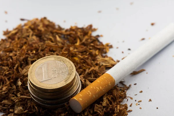 Tabaco desfiado com moedas de euro à volta, isolado sobre fundo branco. O tabaco pode causar doenças no organismo . — Fotografia de Stock