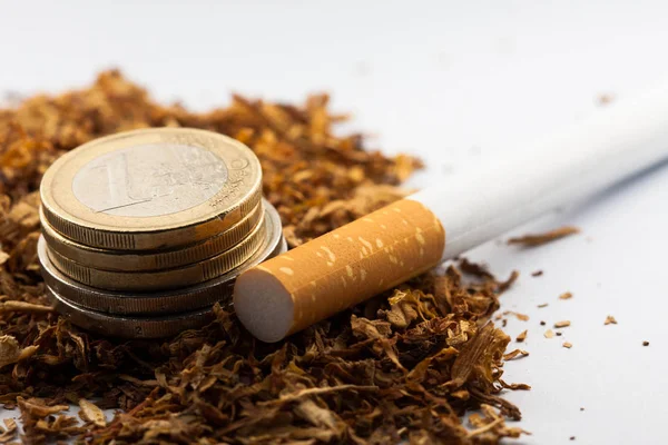 Tabaco desfiado com moedas de euro à volta, isolado sobre fundo branco. O tabaco pode causar doenças no organismo . — Fotografia de Stock