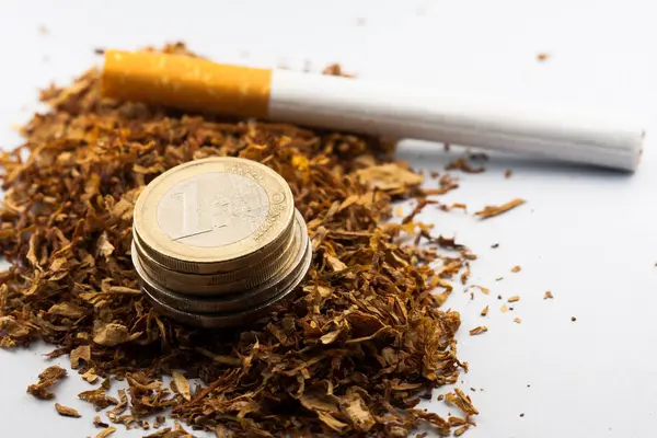 Tabákový tabák s euromincemi, izolovaný na bílém pozadí. Tabák může vyvolat choroby v organismu. — Stock fotografie