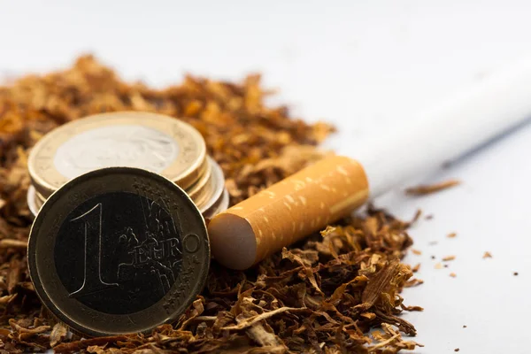 Tabaco desfiado com moedas de euro à volta, isolado sobre fundo branco. O tabaco pode causar doenças no organismo . — Fotografia de Stock