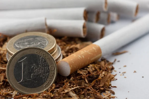 Tabaco desfiado com moedas de euro à volta, isolado sobre fundo branco. O tabaco pode causar doenças no organismo . — Fotografia de Stock