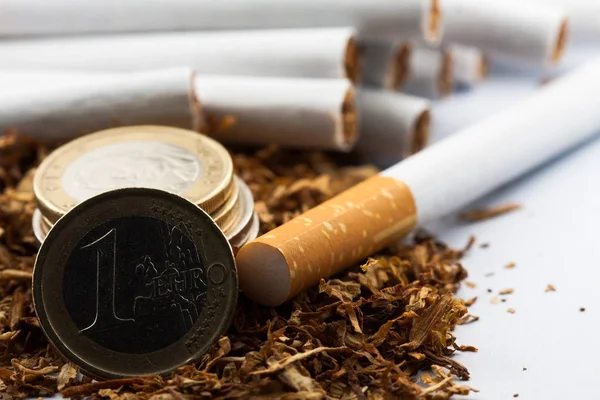 Tabaco desfiado com moedas de euro à volta, isolado sobre fundo branco. O tabaco pode causar doenças no organismo . — Fotografia de Stock