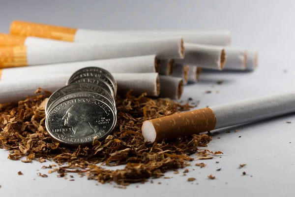 Cigarros separados com algum tabaco desfiado espalhado, com moedas em centavos ao redor, isolado em fundo branco. O tabaco pode causar doenças no organismo. Dói o corpo humano. . — Fotografia de Stock
