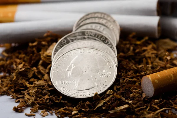 Cigarros separados com algum tabaco desfiado espalhado, com moedas em centavos ao redor, isolado em fundo branco. O tabaco pode causar doenças no organismo . — Fotografia de Stock