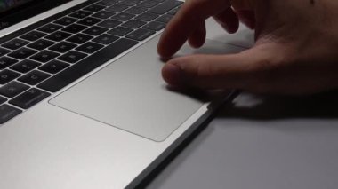 Bir adam dizüstü bilgisayar kullanıyor. Parmaklarınızın trackpad'de hareket ettirilmesi. Dizüstü bilgisayardaki dosyaları yönetme.