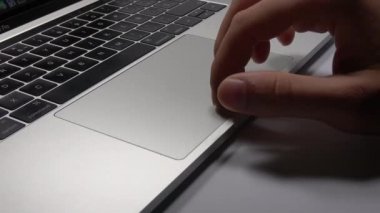 Bir adam dizüstü bilgisayar kullanıyor. Parmaklarınızın trackpad'de hareket ettirilmesi. Dizüstü bilgisayardaki dosyaları yönetme.