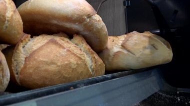 Hd. Yakın kapat genç beyaz kadın ekmek almak için fırından toplar. Genç kadın süpermarketin fırınından ekmek topluyor.