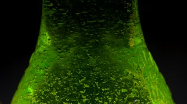 Hd. Yoğuşma bir soda şişesi aşağı yuvarlanan düşer. Şişenin içindeki gaz kabarcıkları. Siyah bir arka plan yeşil soda şişesi üzerinde. ıslak.