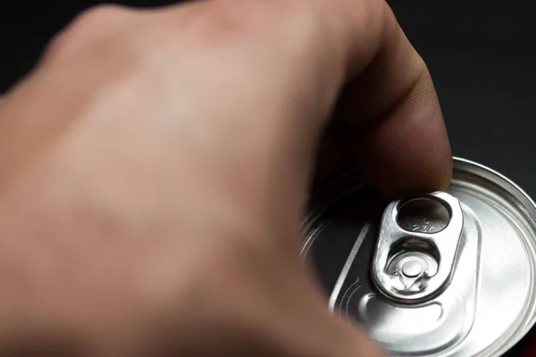 Hand opening a can of cold soda. Finger making strength to open the can. Cold drinks.