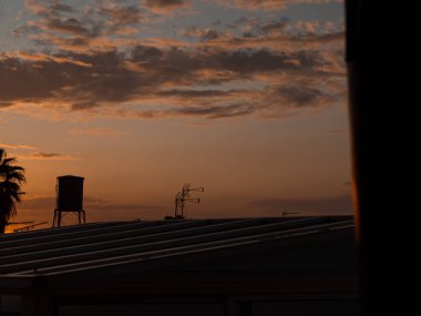 Şiddetli bir yağmur fırtınasından önce. Açık güneş ışığının göründüğü turuncu gün batımı. Gökyüzü bulutlarla kaplıdır, açık mavi gökyüzü ile. Kara bulutlar.