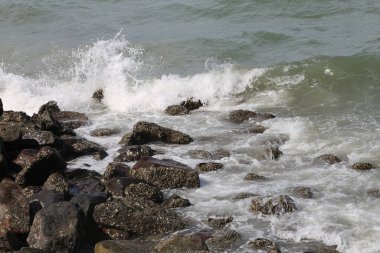 Okyanus dalgaları beyaz kayalara çarpıyor.