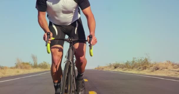 慢动作年轻健康的人骑自行车在沙漠路外面在阳光明媚的天 背景蓝色的天空的道路自行车 — 图库视频影像