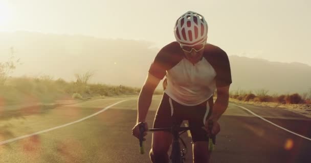 夕暮れレンズ フレアの外の砂漠の道をロードバイクでサイクリング スローモーション若い男 — ストック動画