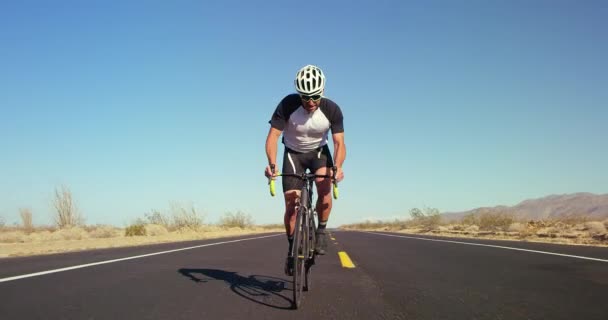 年轻健康的人骑自行车自行车外面的沙漠路在阳光明媚的一天 背景蓝色的天空 — 图库视频影像