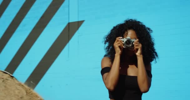 Ung Kvinna Fotografering Med Filmkamera Mot Färgglada Blå Vägg Slow — Stockvideo