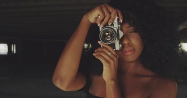 Afrikalı-Amerikalı kadın film kamerası ve çekici fotoğraflar ile oynarken yavaş çekim