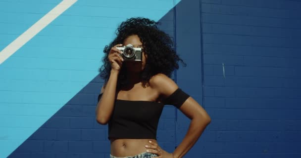 Junge Frau Schießt Fotos Mit Filmkamera Gegen Bunte Blaue Wand — Stockvideo