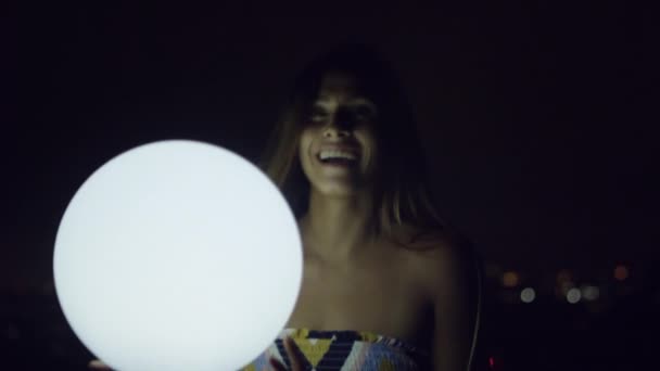 年轻女子手持发光球在黑暗中 — 图库视频影像