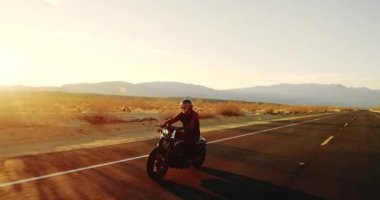 Genç sürme vintage siyah motosiklet çöl otoyol aşağı günbatımında adam.