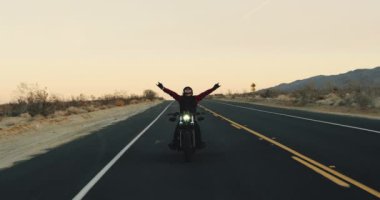 Genç sürme vintage siyah motosiklet çöl otoyol aşağı günbatımında adam.