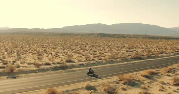 夕暮れ砂漠高速道路乗ってビンテージ黒バイクを若者します — ストック動画