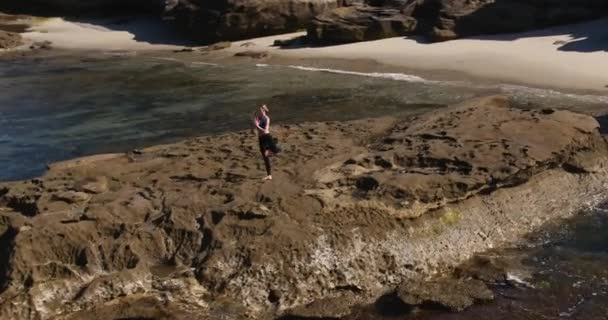 外の晴れた朝にビーチの海岸線でヨガのポーズをしている女性の航空写真 — ストック動画