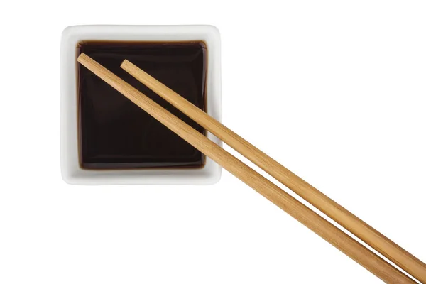 Соевый соус и бамбуковые палочки на белом фоне — стоковое фото
