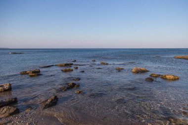 Rodos sahilinde gün batımında ön planda kayalar.