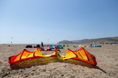 Uçurtma alıştırması yapan insanlar. Prasonisi, Rhodes yarımadasındaki plaj. Deniz kıyısında renkli uçurtmalar. Mavi deniz ve rüzgar sörfü.