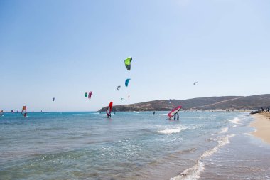 Uçurtma alıştırması yapan insanlar. Prasonisi, Rhodes yarımadasındaki plaj. Deniz kıyısında renkli uçurtmalar. Mavi deniz ve rüzgar sörfü.