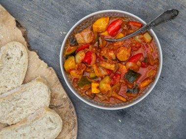 Biberli güveç, kabak ve beyaz ekmekle servis edilen bir kasede vegan sosisi. Karanlık arka plan, yakın plan. Geleneksel Macar yemeği lecho.