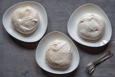 Pavlova 'nın üç beyaz tabakta yaptığı kremalı tatlı kekleri..