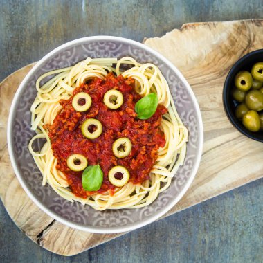 Vejetaryen bolonez soslu spagetti, zeytin, fesleğen ve vejetaryen parmesan ile servis ediliyor..