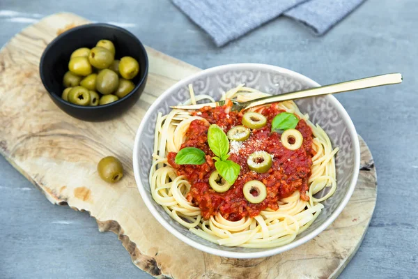 Vejetaryen bolonez soslu spagetti, zeytin, fesleğen ve vejetaryen parmesan ile servis ediliyor..