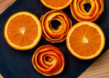 Bir mandalina bir soyma narenciye bir dekor ile koyu bir taş üzerinde servis edilir. Yarım mandalina ve bir tabakta spiral kabuğu. Close. Yumuşak odak. Üstte görüntü.