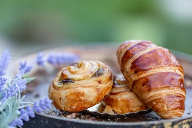 Kuru üzümlü çörekler ve Fransız kruvasan. Tatlı. Lavanta çiçekleri. Yumuşak odak. Bulanık arka plan. Close. Makro.